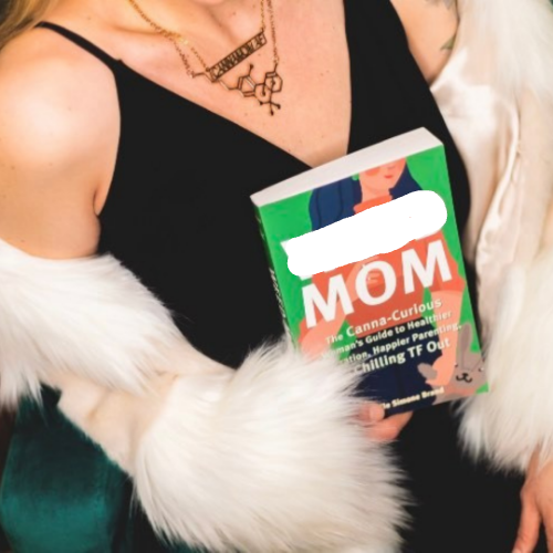Person holding a book titled 'Mom' with colorful cover design.